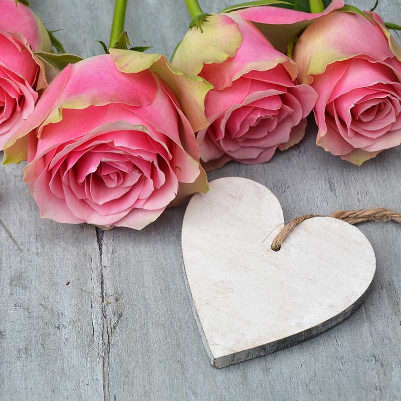 Valentinstag Herz aus Holz mit rosa Rosen auf Holztisch